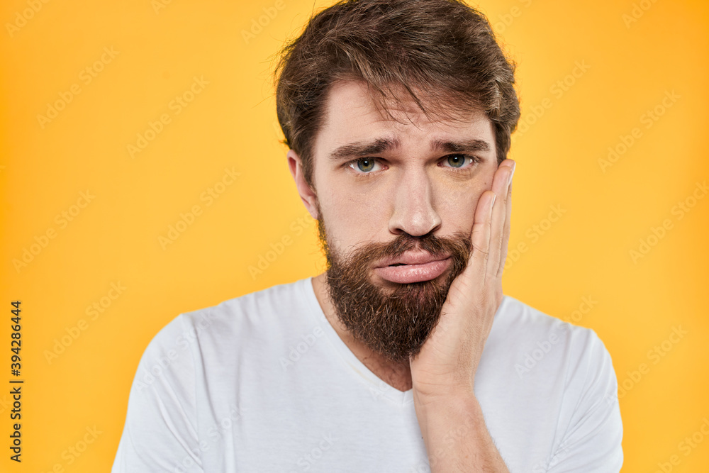 Man with emotional expression white t-shirt close-up studio yellow background