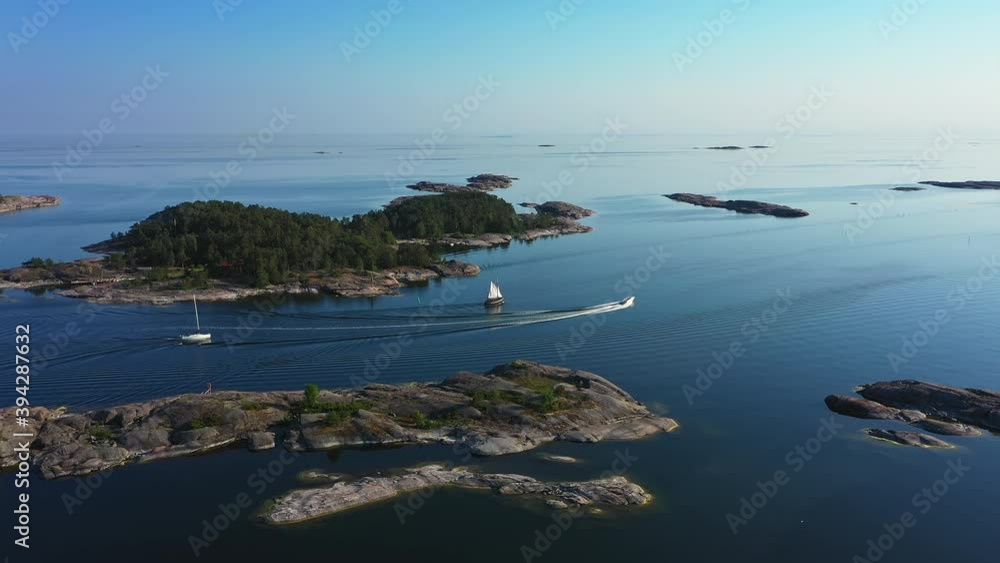 Aerial of Speed Boat Passing Sailboats to Explore Forested Island in Finnish Archipelago Aerial of Speed Boat Passing Sailboats to Explore Forested Island in Finnish Archipelago