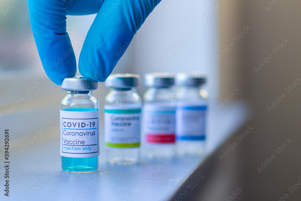 Close up of a health worker wearing globes and reaching a Covid-19 vaccine. Coronavirus vaccine or SARS-CoV-2. Close up of a health worker wearing globes and reaching a Covid-19 vaccine. Coronavirus vaccine or SARS-CoV-2.