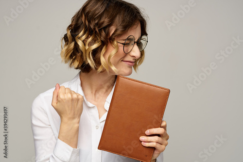 woman with notepad in hands business work beige background glasses hairstyle © SHOTPRIME STUDIO