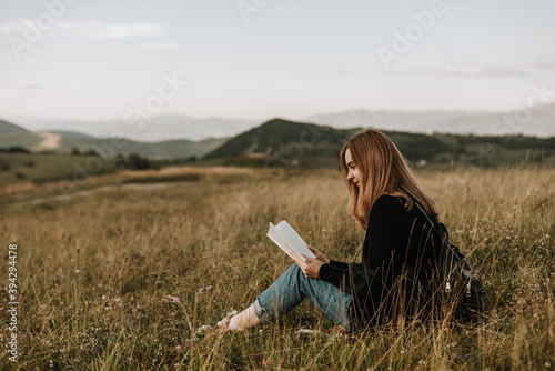 Beautiful woman reading a book in nature on a mountain
