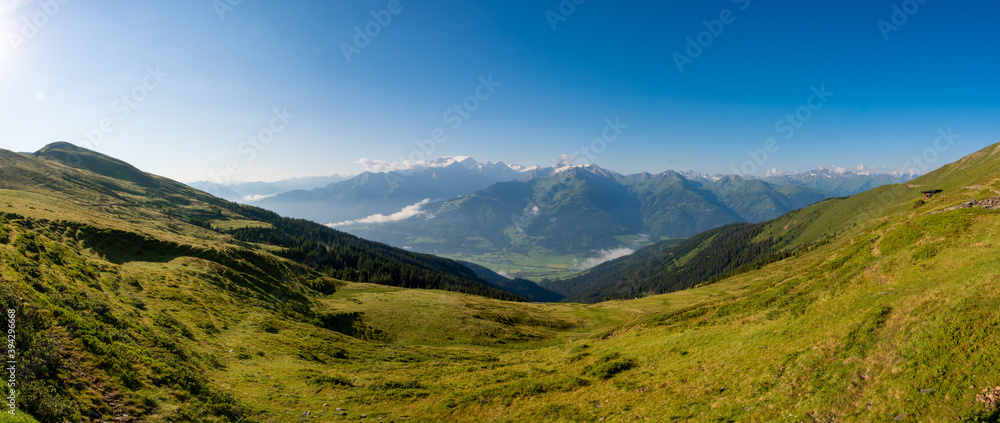 Scenic summer view on snowy grossglockner peak and nordlicher bockkarkees in sunny day with green meadows, pine tree forests, hills, blue sky. Europe alps in austria