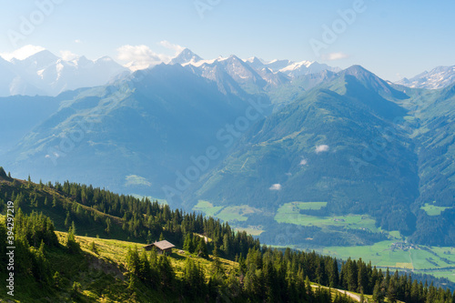 Scenic summer view on snowy grossglockner peak and nordlicher bockkarkees in sunny day with green meadows, pine tree forests, hills, blue sky. Europe alps in austria