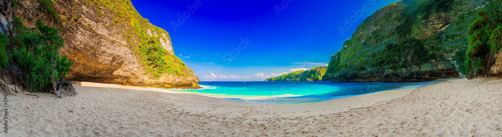 Azure beach with rocky mountains and clear water of Indian ocean at sunny day / A view of a cliff in Bali Indonesia