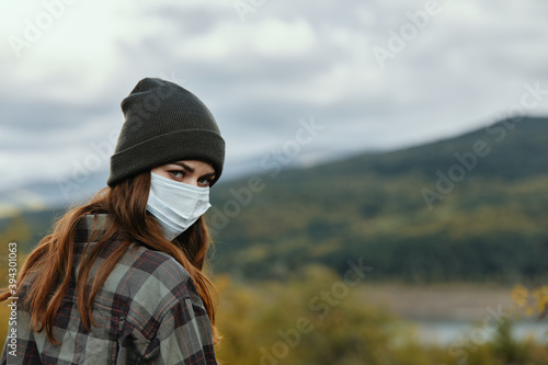 Rear view of a woman in a medical mask and hat in the mountains in nature © SHOTPRIME STUDIO