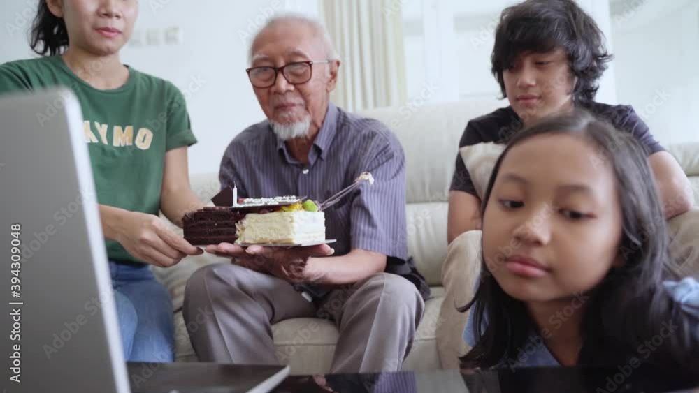 Elderly man having video call by using a laptop while celebrating his birthday party with his family and friends at home. Shot in 4k resolution Elderly man having video call by using a laptop while celebrating his birthday party with his family and friends at home. Shot in 4k resolution