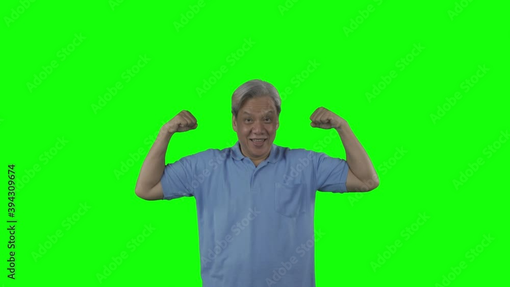 Happy senior man showing his muscle while standing in the studio with green screen background. Shot in 4k resolution Happy senior man showing his muscle while standing in the studio with green screen background. Shot in 4k resolution