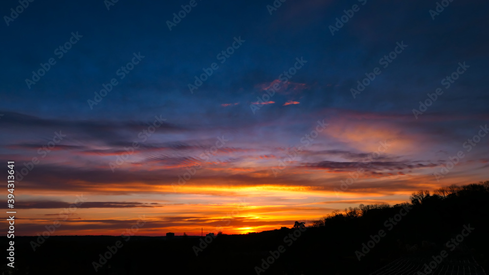 Amazing sunrise in rural scene. Dramatic sky with sunbeam and stratus clouds over the silhouette of hill on the horizon. Amazing sunrise in rural scene. Dramatic sky with sunbeam and stratus clouds over the silhouette of hill on the horizon.