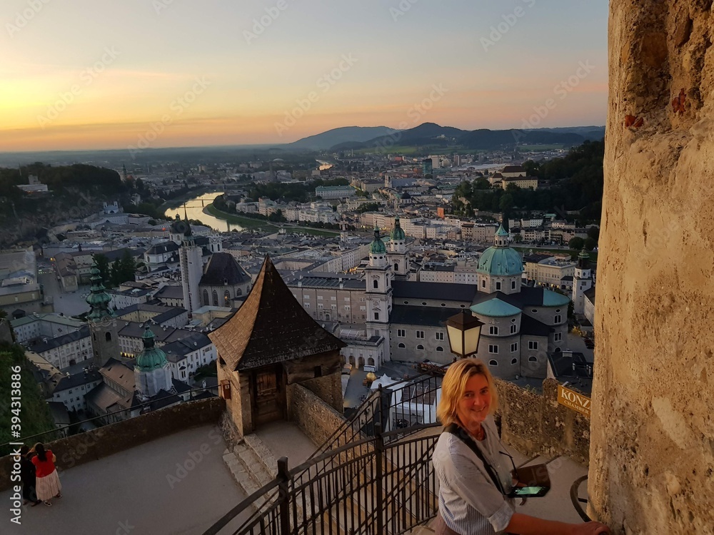 Über den Dächern von Salzburg schaut eine junge Frau direkt in die Kamera und lächelt im Abendlicht