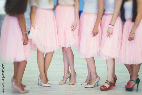 Happy young stylish multiethnic girls having fun during bachelorette bridesmaids party, group of diverse multiracial women dressed in the same coloured dresses clothes, party in pink tones