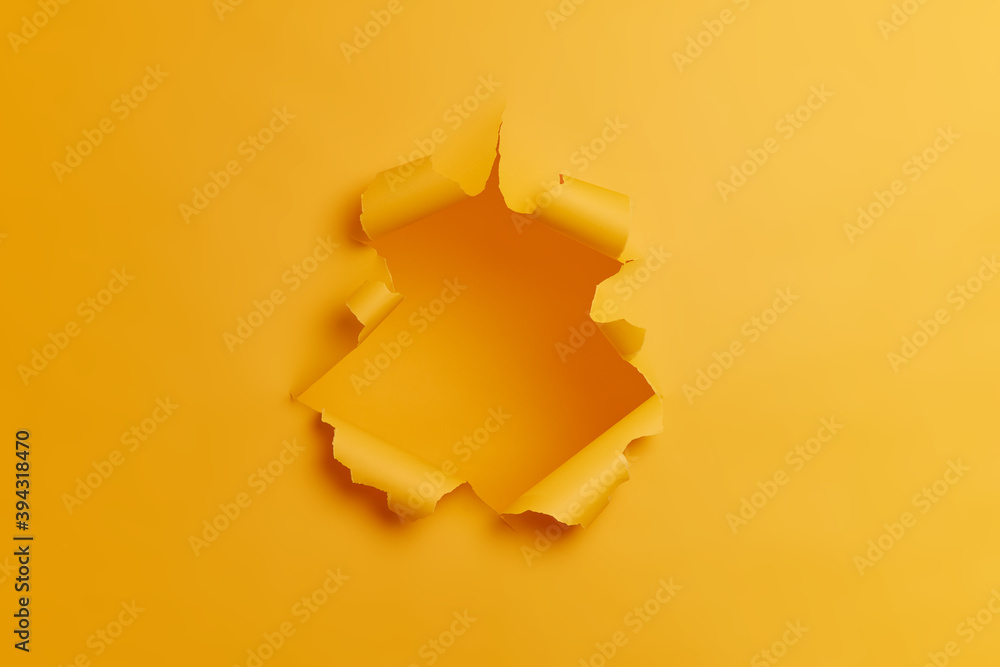 Big paper hole in center of yellow background. Blank space to insert your advertising content promotion or text information. Torn ripped studio wall. Breakthrough concept. No people in shot. - obrazy, fototapety, plakaty 
