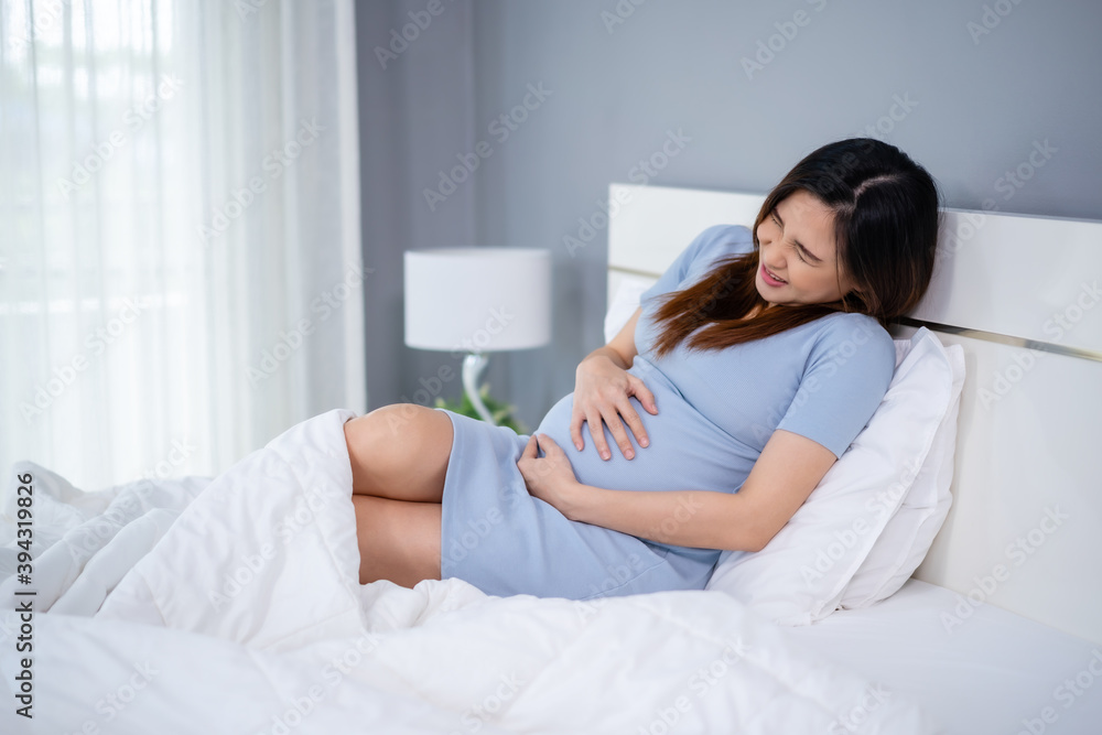 pregnant woman has a stomachache on bed