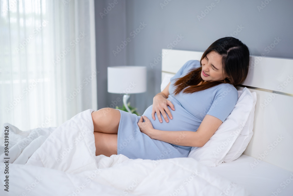 pregnant woman has a stomachache on bed pregnant woman has a stomachache on bed