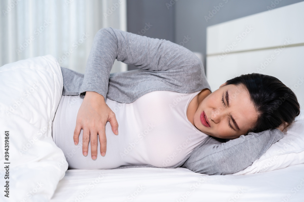 pregnant woman has a stomachache on a bed pregnant woman has a stomachache on a bed