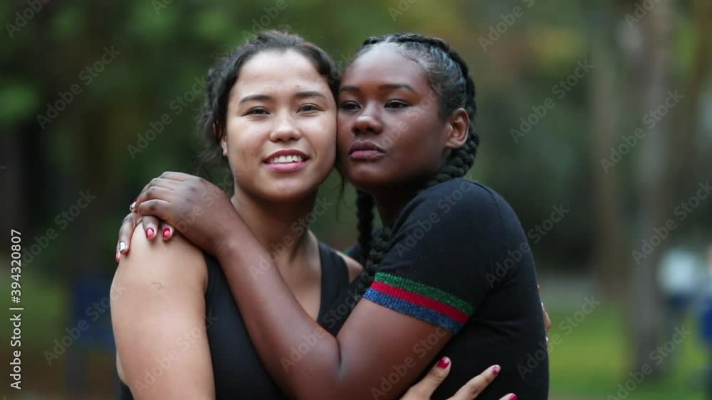 Interracial mixed race girlfriends embrace together outdoors faces Interracial mixed race girlfriends embrace together outdoors faces