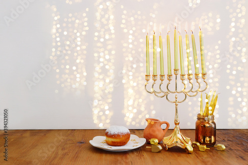 Image of jewish holiday Hanukkah with menorah (traditional Candelabra), donut and wooden dreidel (spinning top)