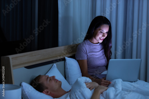 Woman sitting on bed in the night and using laptop computer