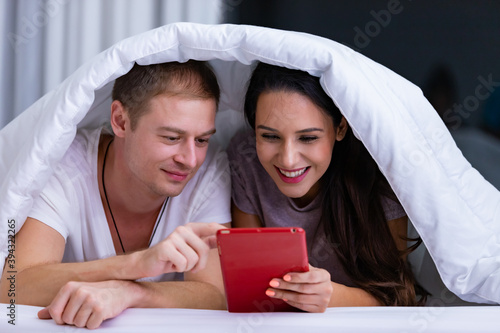 Portrait of young happy playful couple relaxing in comfortable cozy bed.