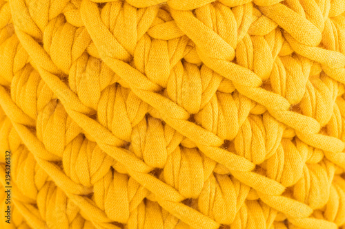Knitted fabric braids. Handmade sweater. Cotton jersey background, with an embossed pattern of a yellow background. Hand-knitted wool pattern