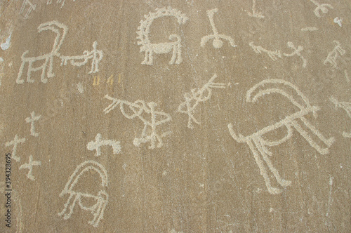 Ibex and men with guns carving on rock: detail of ancient silk road era petroglyphs above Langar village in the Wakhan Corridor in the Gorno-Badakshan Pamir region of Tajikistan