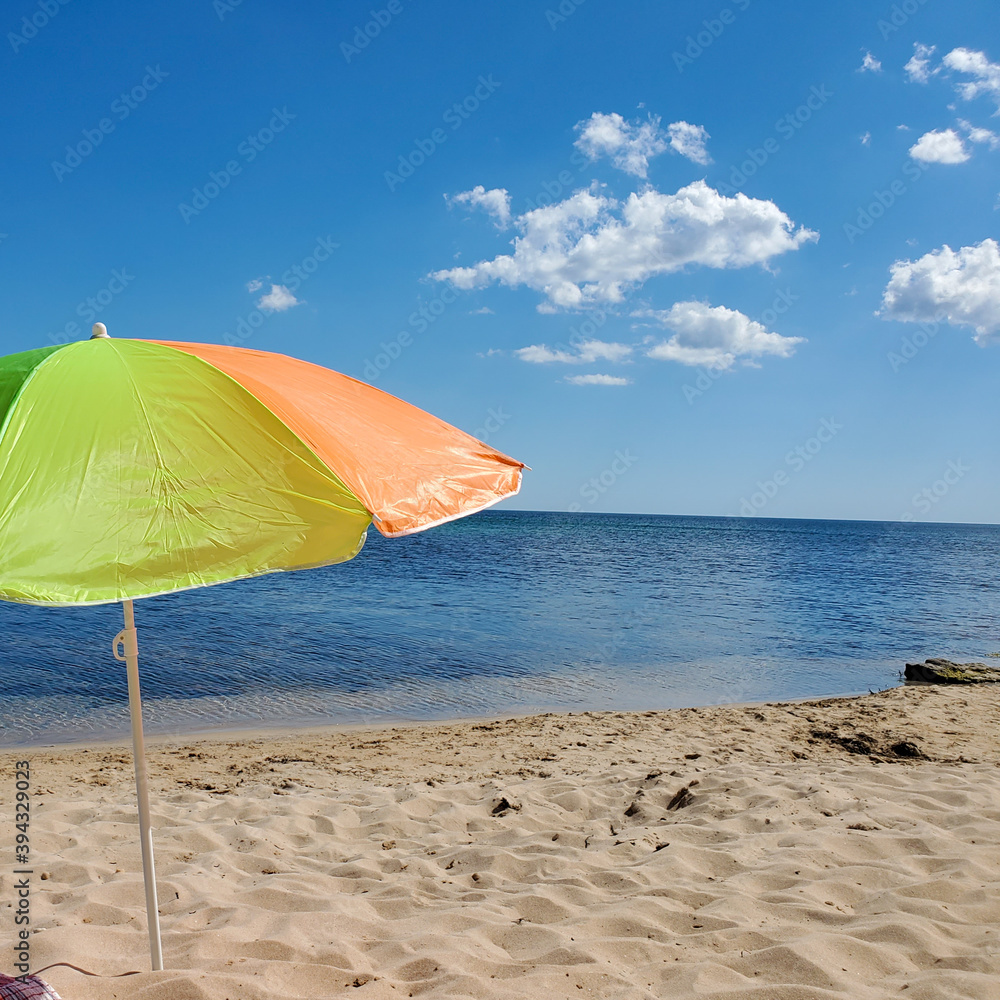 sun umbrella on a sandy beach with turquoise sea and blue sky on a Sunny summer day.