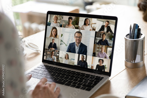 Close up back view of worker talk with multiracial businesspeople on video call at home office. Female employee have webcam digital virtual conference online meeting with diverse colleagues. photo