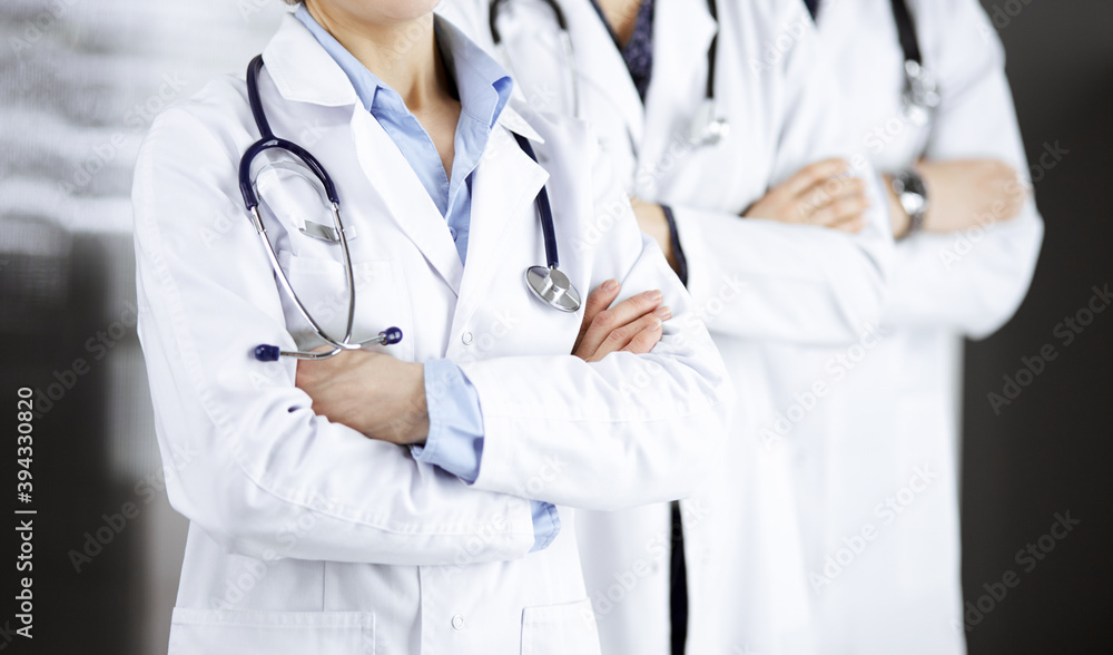 Group of modern doctors standing as a team with arms crossed in hospital office and ready to help patients. Medical help, insurance in health care, best disease treatment and medicine concept Group of modern doctors standing as a team with arms crossed in hospital office and ready to help patients. Medical help, insurance in health care, best disease treatment and medicine concept