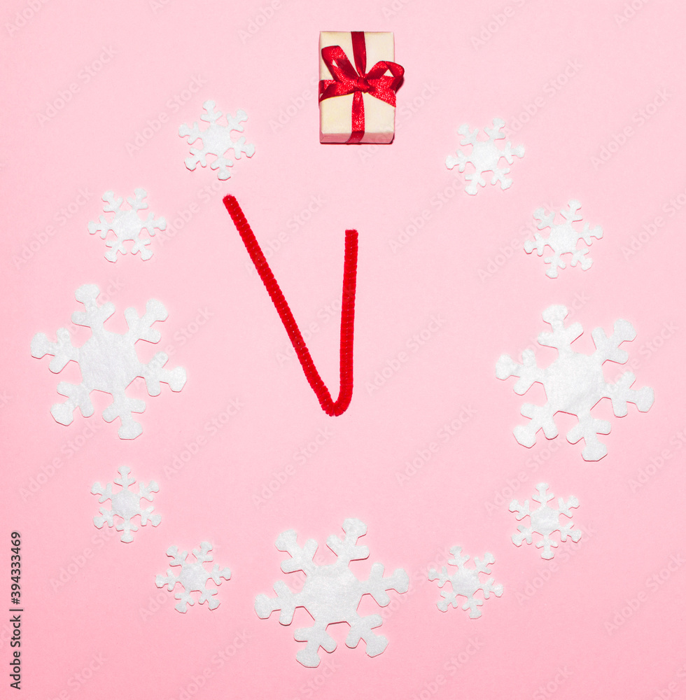 Сhristmas clock made of snowflakes arranged in a circle on a pink background. The time is eleven fifty-five. Concept of time before starting new year, giving presents and gifts Сhristmas clock made of snowflakes arranged in a circle on a pink background. The time is eleven fifty-five. Concept of time before starting new year, giving presents and gifts