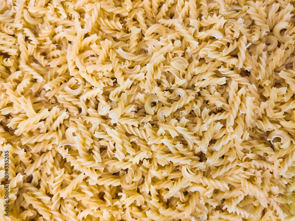 Raw pasta close-up. Spiced Italian pasta is sprinkled in large quantities.