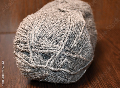 A skein gray yarn close-up on a dark brown background