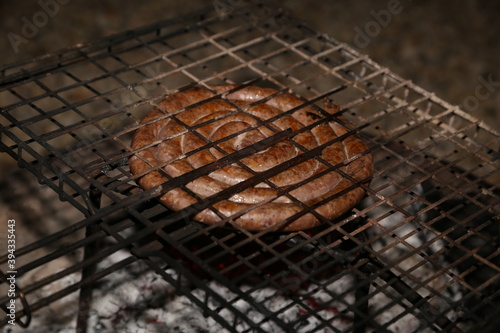 South African boerewors (traditional sausage) being grilled on a braai (Barbeque). This photo has selective focus.  photo