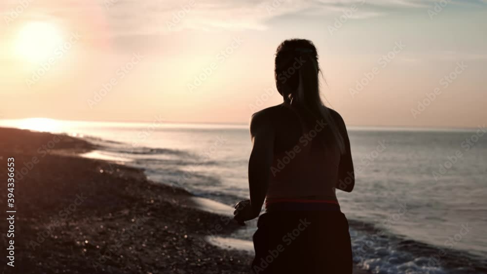 Silhouette of sportswoman running on morning nature beach back view. Shot with RED camera in 4K Silhouette of sportswoman running on morning nature beach back view. Shot with RED camera in 4K