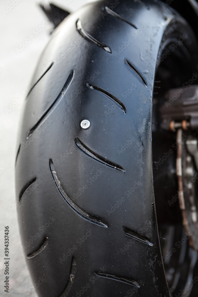 Puncture of rear wheel of motorcycle, steel screw is in tyre, vertical image