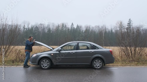 Man opening car hood and looking at engine.