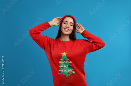 Young woman in Christmas sweater and hat on blue background © New Africa