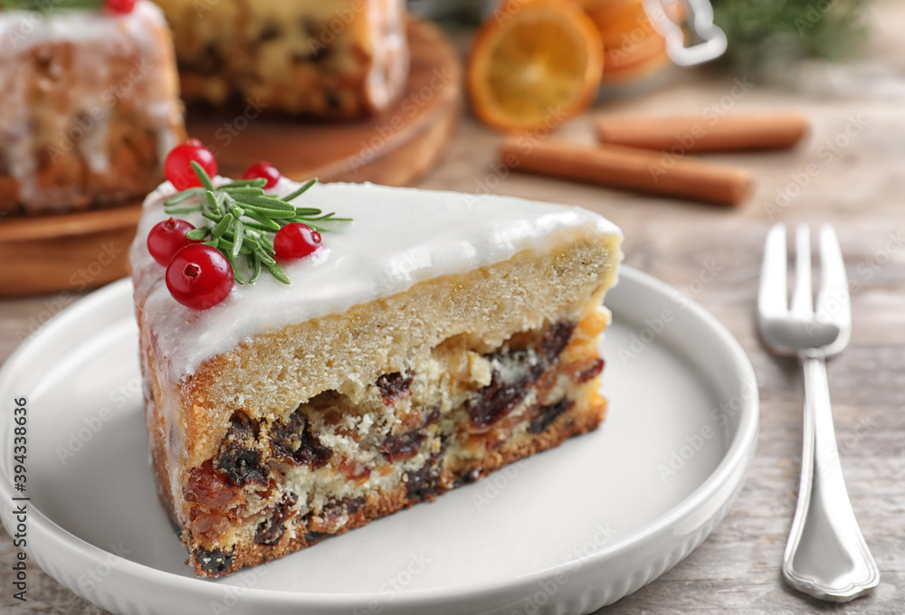 Slice of traditional Christmas cake decorated with rosemary and cranberries on table, closeup Slice of traditional Christmas cake decorated with rosemary and cranberries on table, closeup