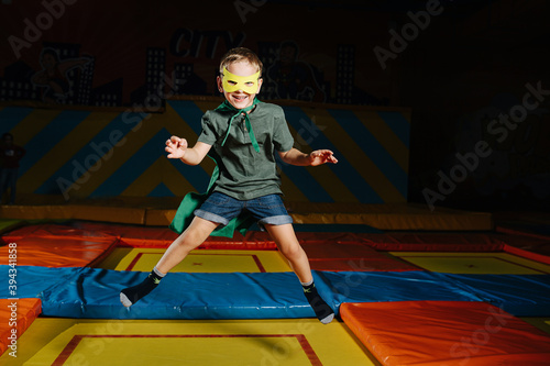 Mischievous confident boy in mask jumping on trampoline in entertainment center
