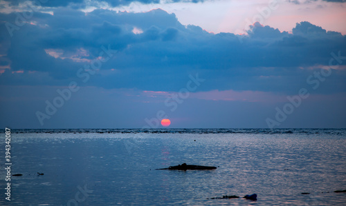 Red Sun disc at sunset in the clouds over the Indian Ocean, Bali island, Indonesia