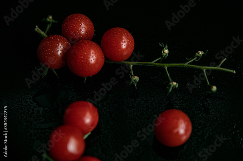 Cherry tomatoes on a twig, not quite fresh on a black glass background