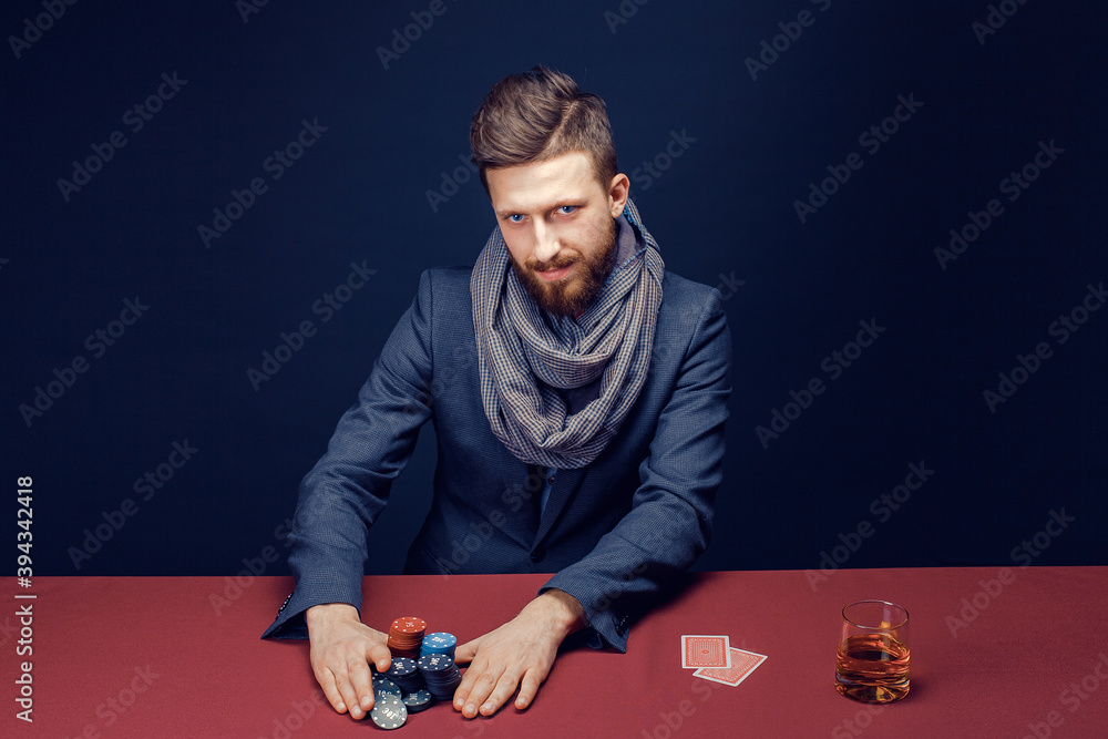 Stylish bearded Man in suit and scarf playing in dark casino, smoking cigar, drink whiskey. Stylish bearded Man in suit and scarf playing in dark casino, smoking cigar, drink whiskey.