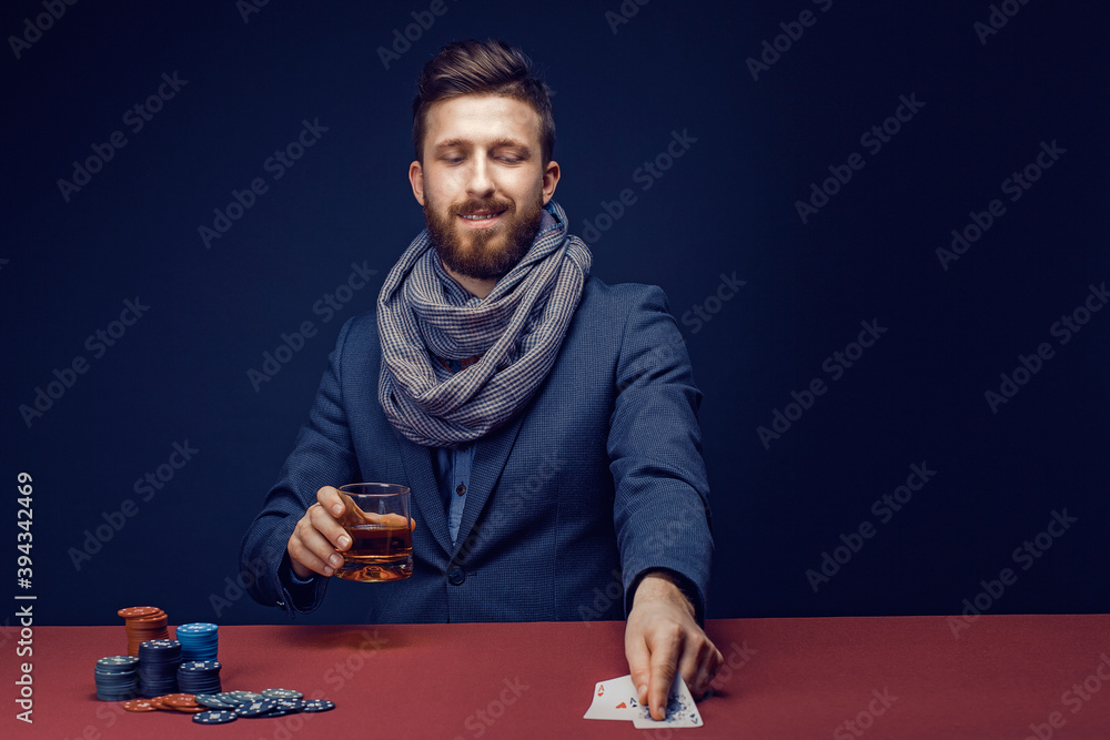 Stylish bearded Man in suit and scarf playing in dark casino, smoking cigar, drink whiskey. Stylish bearded Man in suit and scarf playing in dark casino, smoking cigar, drink whiskey.