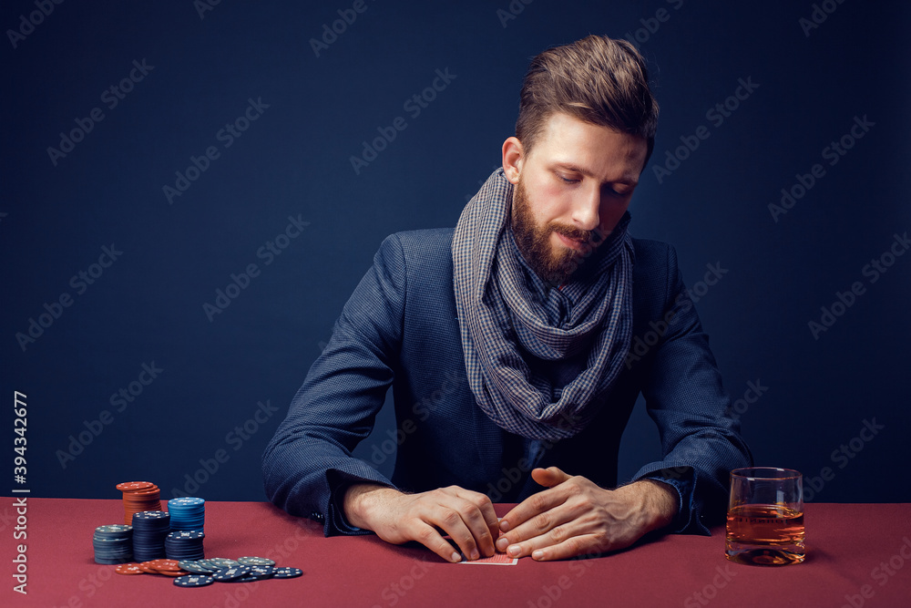 Stylish bearded Man in suit and scarf playing in dark casino, smoking cigar, drink whiskey. Stylish bearded Man in suit and scarf playing in dark casino, smoking cigar, drink whiskey.