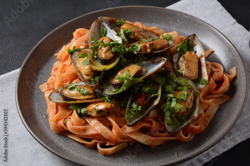 Pasta in tomato sauce with fried mussels, and herbs