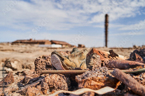 old worn down shoe with an abandoned saltpeter mining town in the blurry background the Atacama desert of Chile, South America photo