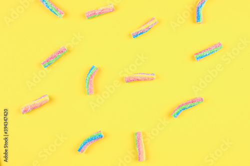 Rainbow jelly candies on a yellow background.