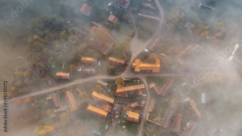 Aerial view of a small village in fog.Top view of traditional housing estate in Czech.Looking straight down with a satellite image style.Houses from above, real estate concept.Foggy landscape © Eva