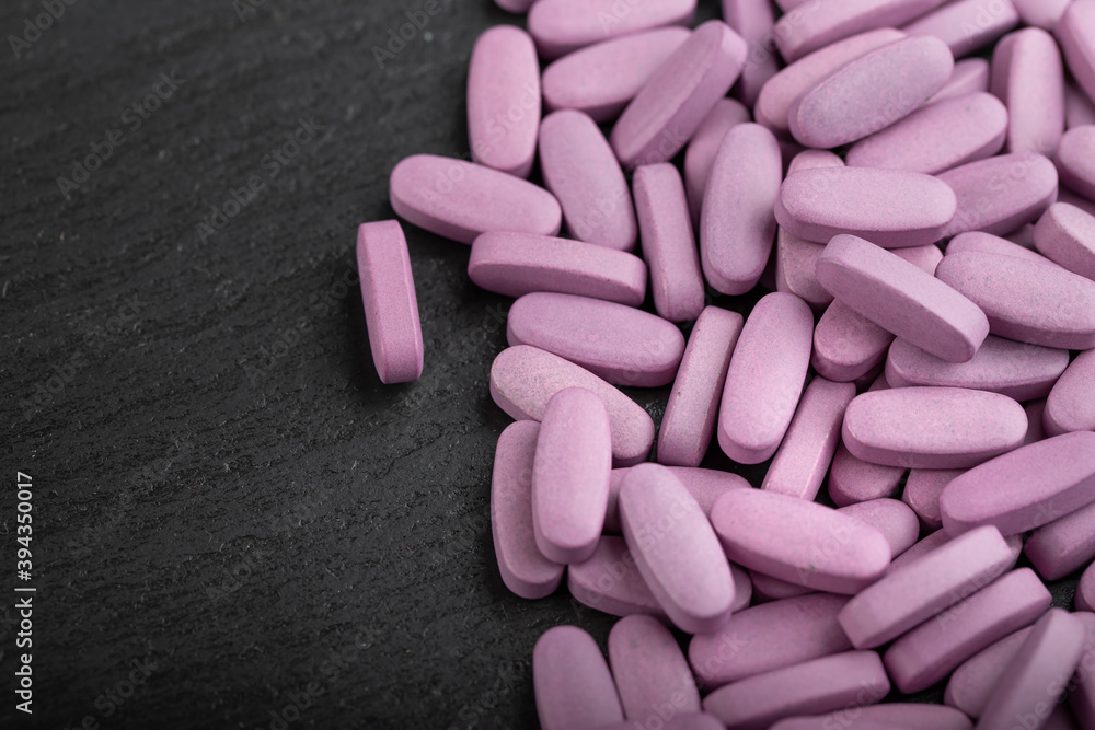 Pink pills on a black background. Health care concept. Space for text. Conservative medicine. Pink pills on a black background. Health care concept. Space for text. Conservative medicine.
