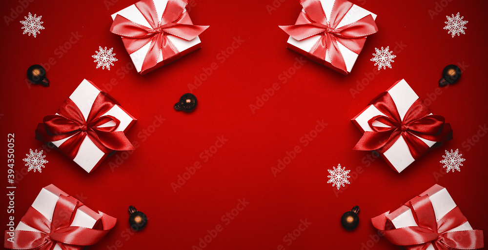 Gift ribbon box. White gift box with scarlet ribbon, New Year balls and sparkling lights in Christmas composition on dark red background for greeting card. Christmas, winter, new year concept.