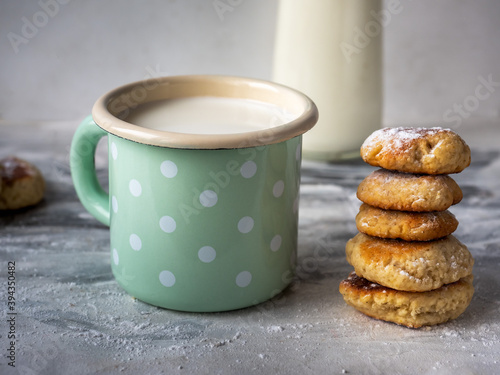 Milk in an enamel mug with peas and a slide of homemade cookies close-up