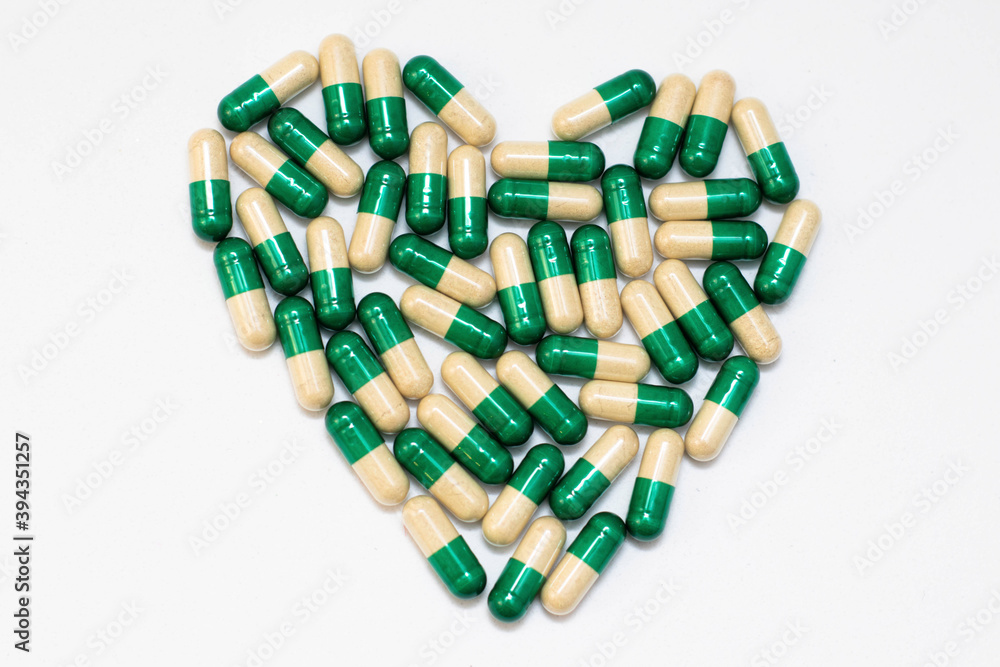The tablets and capsules are laid out in the shape of a heart. Dietary supplements, disease prevention. The photo